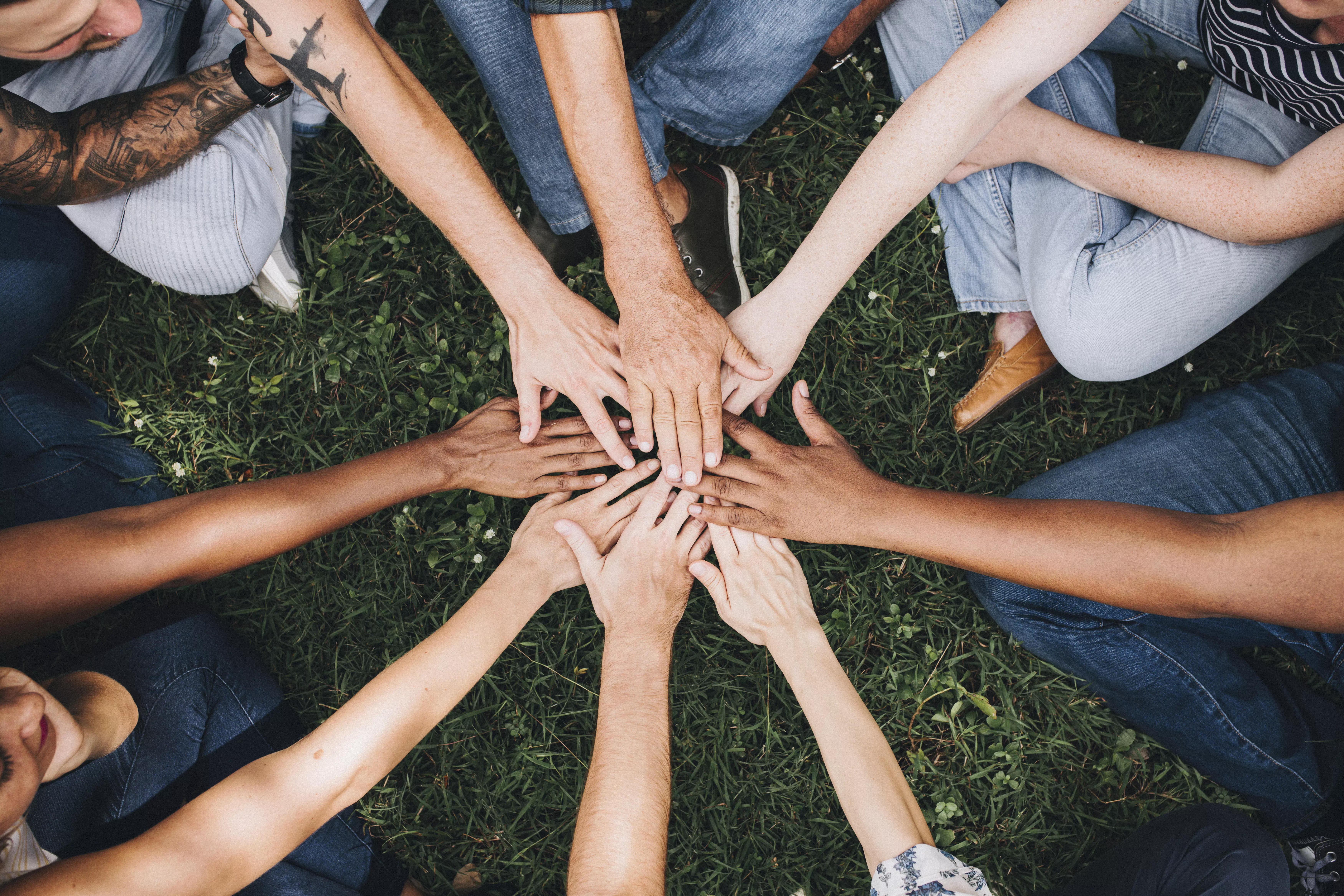 Un grupo de personas uniendo sus manos en señal de unidad y trabajo en equipo.